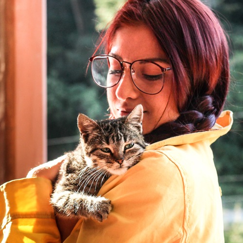 A woman in a yellow rain coat holding a kitty